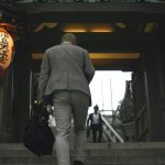 Japanese businessman ascending a staircase in Tokyo, Japan. Captured from behind with lanterns and traditional architecture.