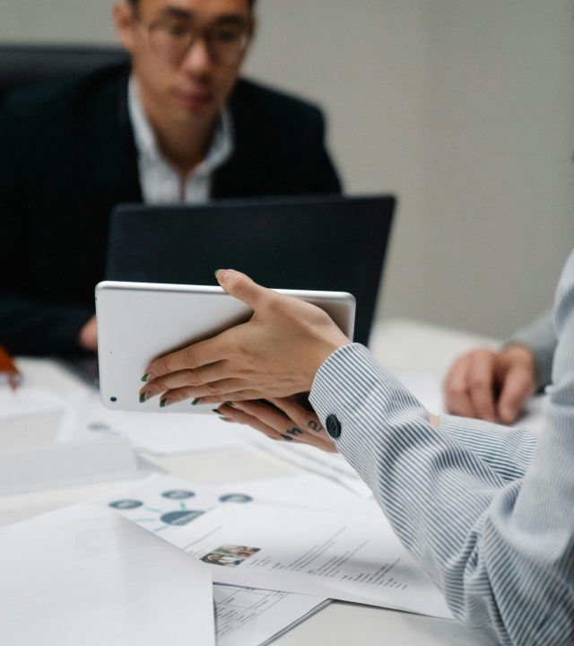Professionals working with a digital tablet and documents in a modern office setting.
